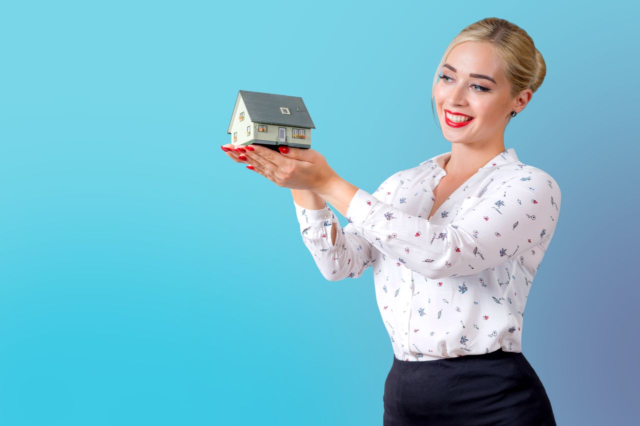 Woman holding a house model — mortgage calculator guide 2026